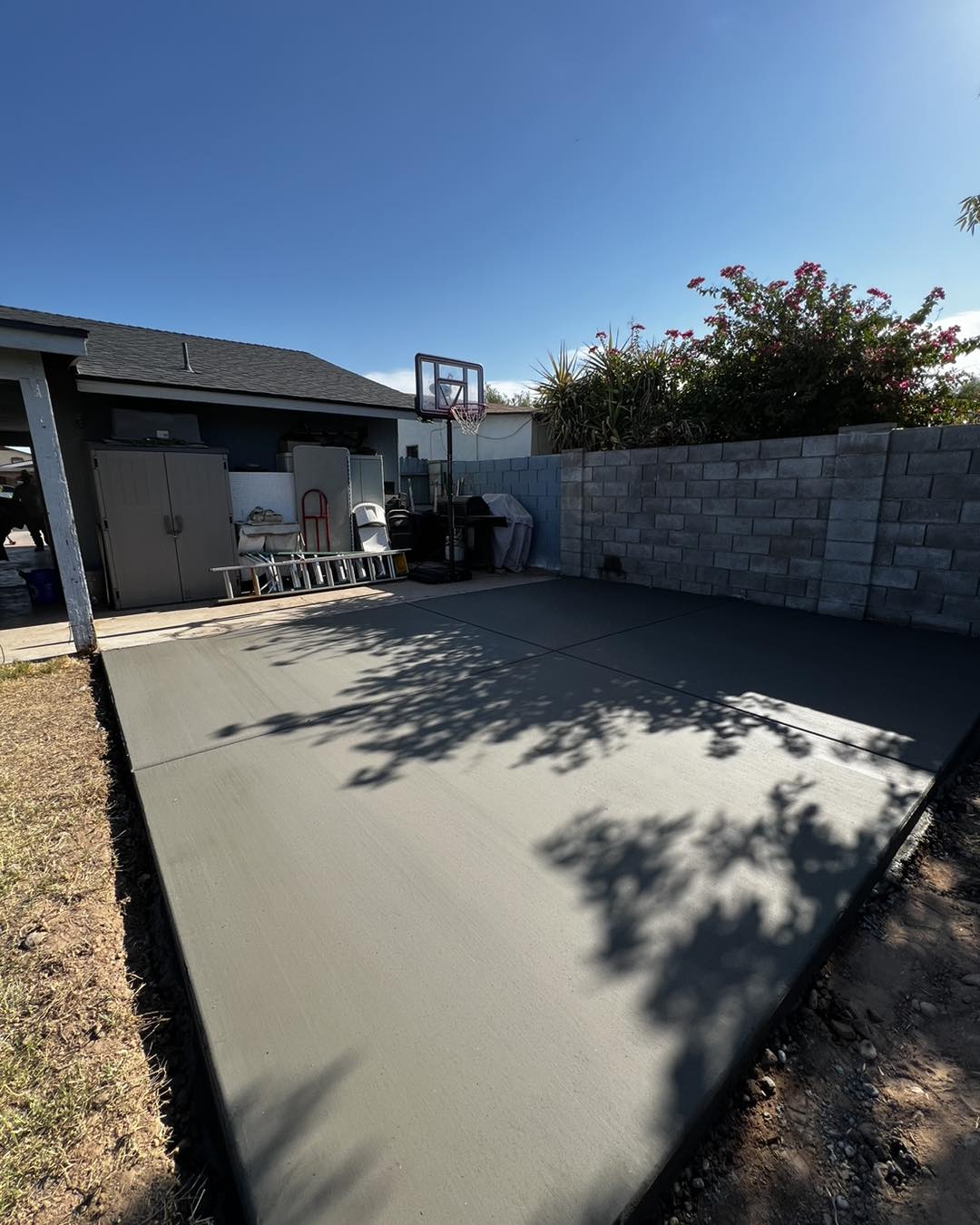 Freshly poured concrete backyard slab next to a block fence in Phoenix, Arizona
